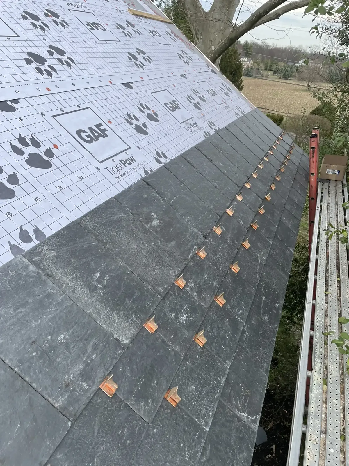 Close-up of slate roof tiles with copper clips during installation
